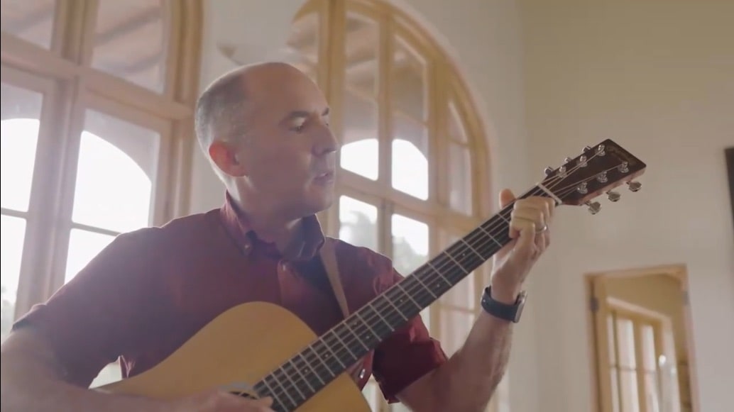 a man playing guitar in front of a window