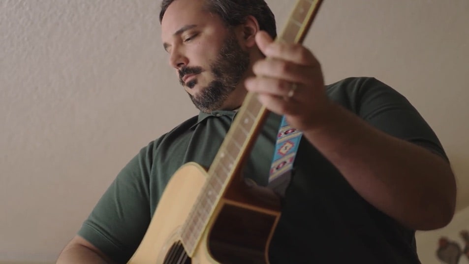 close up on a man playing guitar with eyes closed